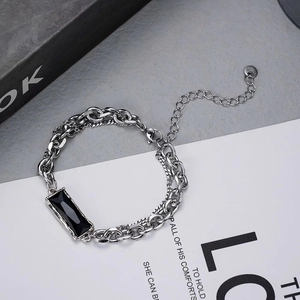 Détail d'un bracelet double chaîne argenté pour homme avec une pierre noire