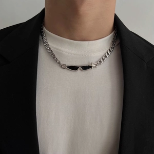 Detail of silver Cuban link necklace with black sunglasses pendant on a male model