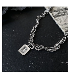 Detail of silver chain necklace featuring a rectangular zircon pendant in punk style