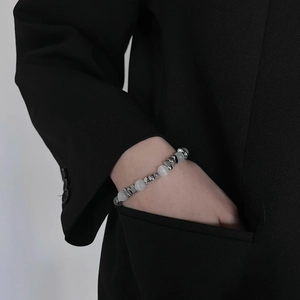 Détail de perles métalliques argentées et perles d'opale sur un bracelet en acier titane