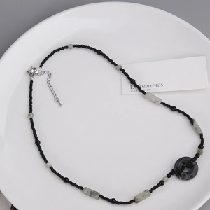 Dettaglio della collana di perline con pendente in marmo grigio e chiusura su piatto