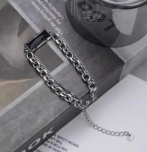 Détail d'un bracelet double couche argenté avec pierre noire sur fond de magazine