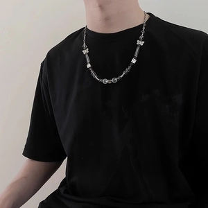 Gros plan du collier avec pendentifs papillon et dés et perles variées sur un mannequin