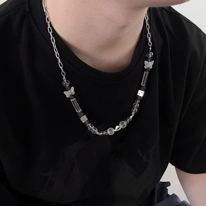 Gros plan du collier de perles avec dés métalliques et pendentifs papillon porté