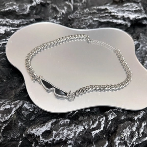 Close-up of silver Cuban chain with black rhinestone pendant on industrial rock
