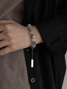 Détail du bracelet en œil de chat avec perles en métal poli et étiquette de marque