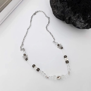 Détail d'un collier de perles avec breloques papillon et cœur contre une roche volcanique