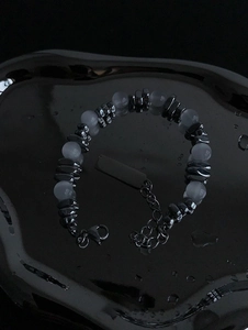Détail d'un bracelet de perles avec perles métalliques noires, opales et plaque