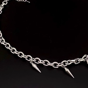 Makroaufnahme einer Punk-Kette mit polierten silbernen Metallspikes auf schwarzem Hintergrund
