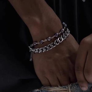 Détail d'un bracelet gourmette en acier titane double couche avec perles et plaque