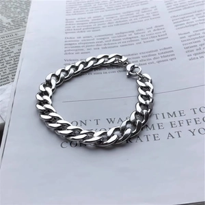 Gros plan d'un bracelet gourmette en acier titane poli argenté avec fermoir mousqueton