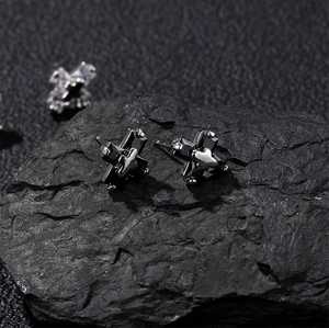 Vue macro de boucles d'oreilles croix avec zircon noir sur une surface rocheuse sombre