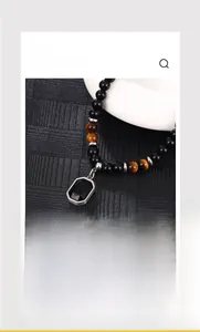 Detail of beaded necklace featuring tiger eye stones and octagonal black gem pendant