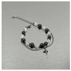 Detail of double-layer beaded bracelet with star pendant on metallic surface