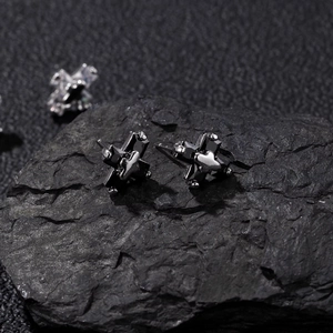 Boucles d'oreilles clous croix en zircon noir pour homme sur une texture de pierre noire