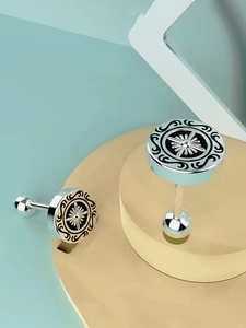 Detail of silver stud earrings with black enamel star pattern and screw back closure