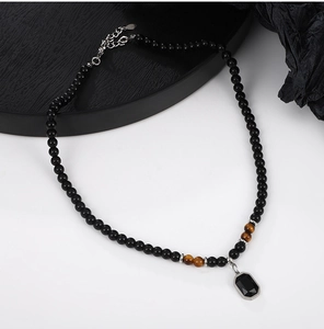 Detail of beaded black onyx necklace with tiger eye stones and a hexagonal pendant