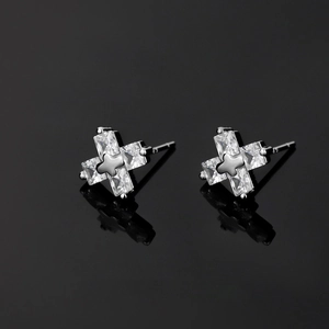 Clous d'oreilles en forme de croix en zircon et métal argenté sur fond noir brillant