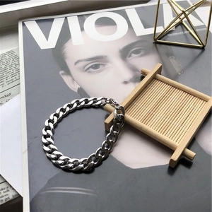 Bracelet gourmette épaisse pour homme en acier inoxydable argenté posé sur un magazine