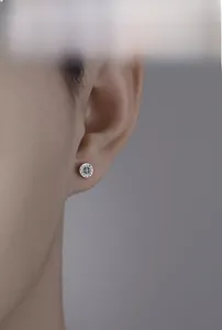 Close-up of vintage silver cross helm stud earring on model with matte metallic finish