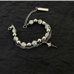 Detail of double-layer punk bracelet with star pendant and ice-cracked beads on black background
