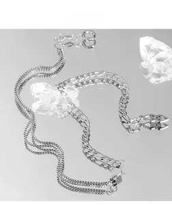 Detail of layered box and Figaro chain necklace with a geometric hollow pendant