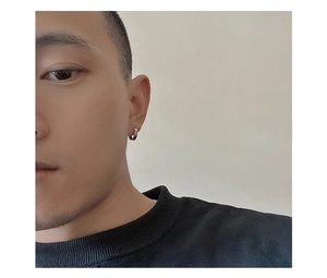 Close-up of minimalist silver titanium steel hoop earring with Greek fret pattern on male model