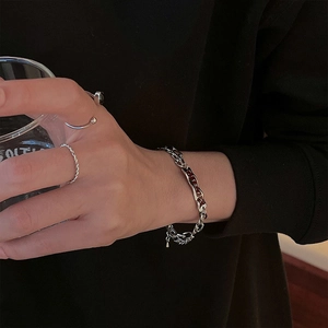 Détail d'un bracelet à double chaîne argentée et d'un ensemble de bagues style hip-hop
