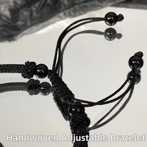 Detailed view of hand-woven adjustable black rope bracelet with polished bead accents