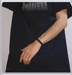 Gros plan d'un bracelet de perles noires minimaliste porté par un mannequin