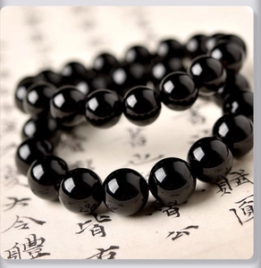 Détail d'un bracelet en perles de verre noir poli avec une texture de surface lisse et brillante