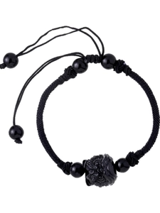 Close-up of hand-woven black cord bracelet with carved beast charm and adjustable slide knot