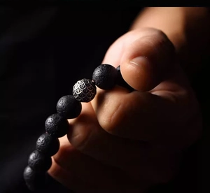 Close-up of volcanic lava stone beads and a detailed silver scale textured metal bead