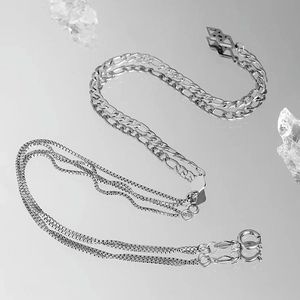 Silver mixed-link necklace featuring Figaro and multi-strand chains on a mirror surface