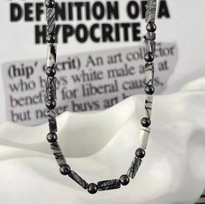 Minimalist beaded necklace with black and white stone cylinders and metallic beads