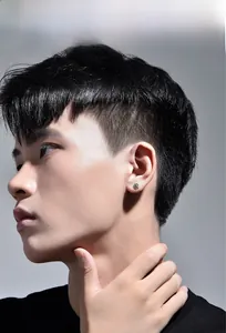Detail display of silver sunburst stud earrings on male model with a minimalist style