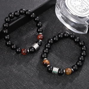 Dettaglio macro di bracciali in occhio di tigre e ossidiana nera con accenti in argento