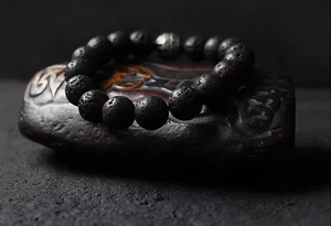 Macro detail of textured black lava stone beads and silver hollow metal bead