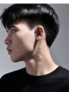 Close-up of men's silver sunburst stud earring with black detail on model's ear