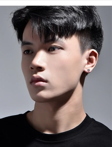 Close-up of a silver sunburst earring worn by a male model on a dark background