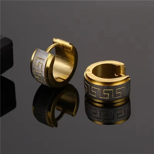 Macro detail of men's titanium steel hoop earring with golden Greek fret pattern