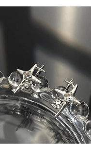 Macro shot of silver star-shaped stud earrings with square inset crystals and fine metalwork