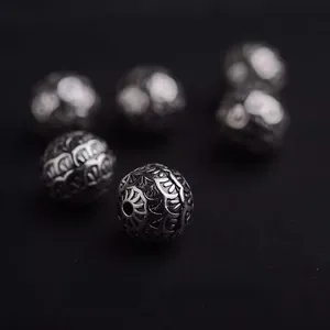 Macro detail of vintage engraved silver beads with intricate scale patterns and antique finish