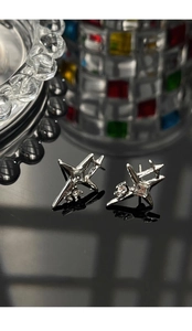 Macro shot of silver starburst stud earrings with centered clear zircon on black surface
