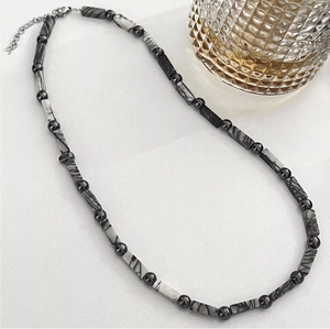 Detailed view of neutral stone bead necklace with black and white texture and metal beads