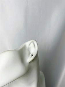 Minimalist silver star stud earring shown on a white ear model with macro detail