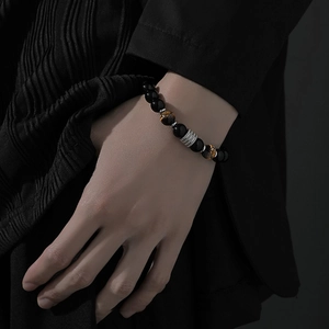 Dettaglio del bracciale di perle con pietre occhio di tigre e ciondoli in metallo argentato