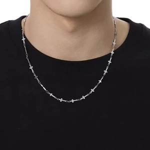 Dettaglio di una collana a catena con croce d'argento su una maglietta nera sobria