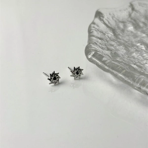Silver sun-shaped stud earrings with black center stone on a minimalist background