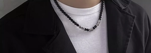 Dettaglio della collana di perle con pietre occhio di tigre e cilindro in metallo inciso